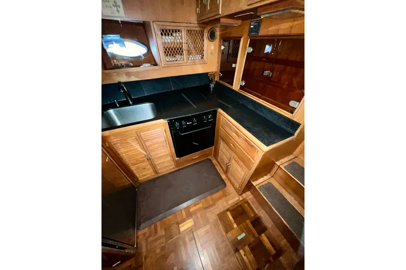 Slide: The Image of 1987 Lien Hwa 47 Cockpit Motor Yacht kitchen with wood cabinetry and black countertops. - 6