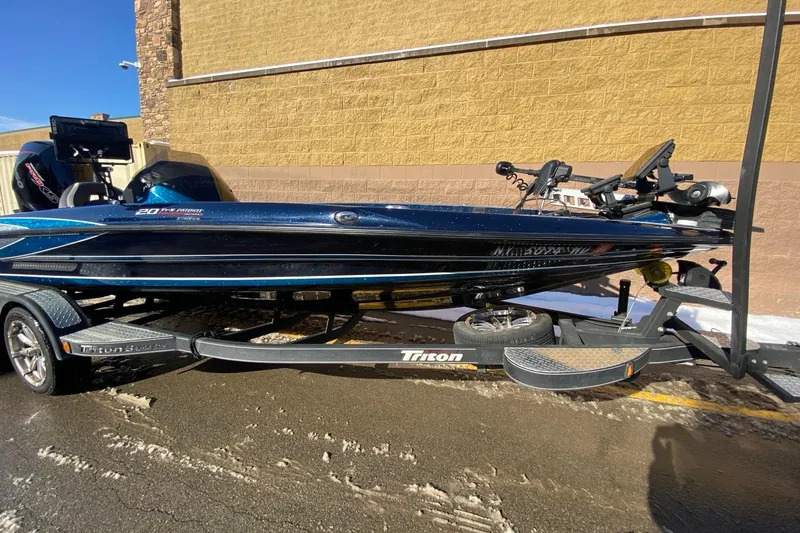Slide: The Image of 2020 Triton 20 TrX Patriot boat on trailer, parked outdoors. - 2