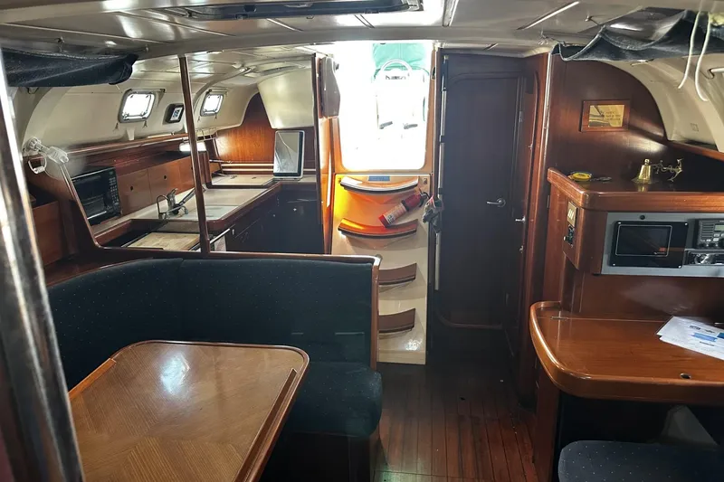 Slide: The Image of Interior of 1994 Beneteau Oceanis 400 sailboat, featuring wood finishes and cozy seating area. - 13
