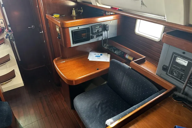 Slide: The Image of Navigation station inside 1994 Beneteau Oceanis 400 sailboat, featuring wood finish and communication equipment. - 16