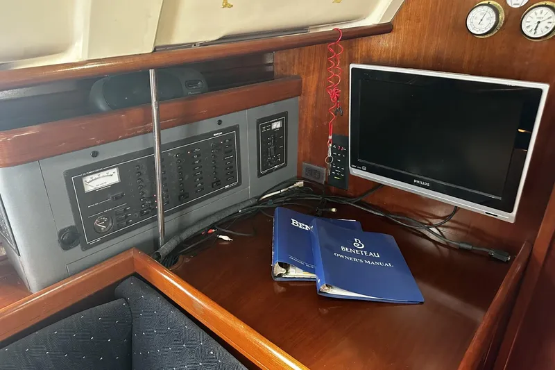 Slide: The Image of Interior of 1994 Beneteau Oceanis 400 with control panel, monitor, and manuals. - 19