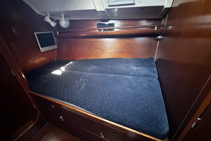 Slide: The Image of 1994 Beneteau Oceanis 400 cabin interior with dark wood and blue bedding. - 30