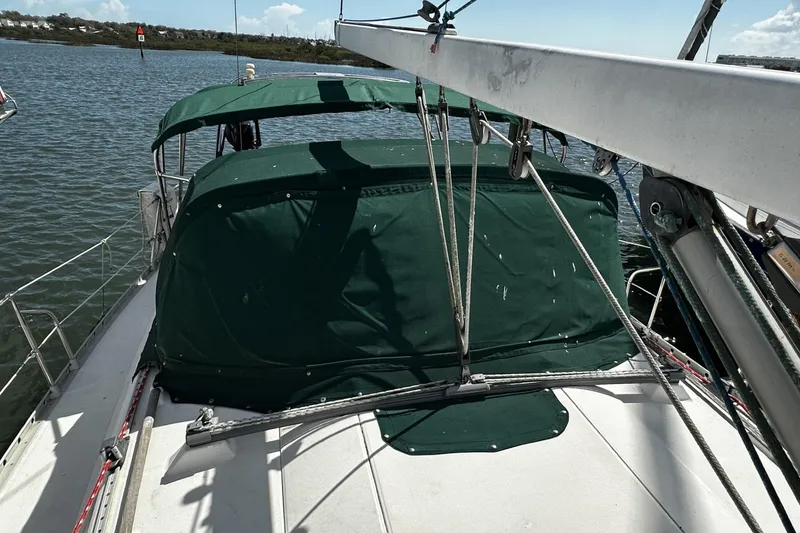 Slide: The Image of 1994 Beneteau Oceanis 400 sailboat with green canopy, docked on calm waters. - 44