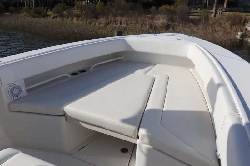 Slide: The Image of 2013 Jupiter 30 boat interior with cushioned seating and speaker, docked by the water. - 20