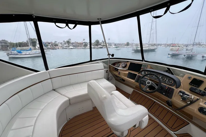 Slide: The Image of 2003 Carver 444 Cockpit Motor Yacht interior with helm and seating, overlooking marina. - 13