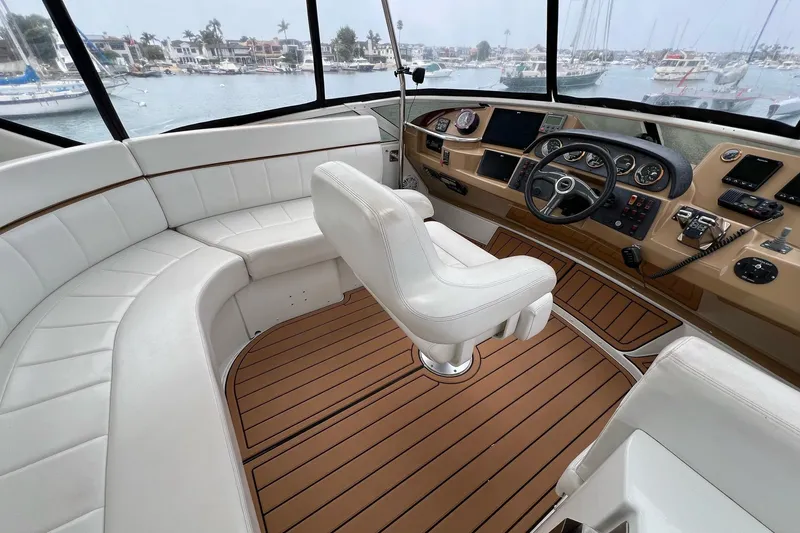 Slide: The Image of 2003 Carver 444 Cockpit Motor Yacht interior with helm, white seating, and wood flooring. - 14