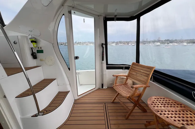 Slide: The Image of 2003 Carver 444 Cockpit Motor Yacht interior with wooden chairs and scenic water view. - 29