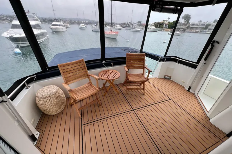 Slide: The Image of 2003 Carver 444 Cockpit Motor Yacht with wooden chairs, table, and marina view. - 30