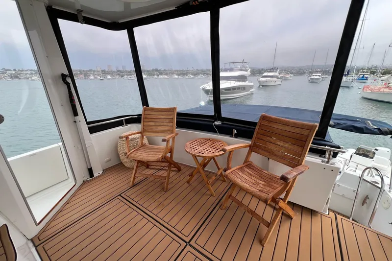 Slide: The Image of 2003 Carver 444 Cockpit Motor Yacht interior with wooden chairs and table, overlooking marina. - 31