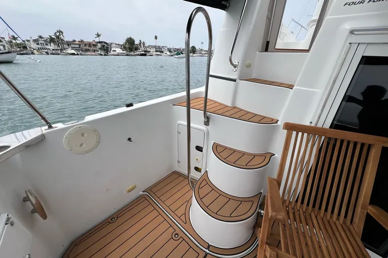 Slide: The Image of 2003 Carver 444 Cockpit Motor Yacht with wooden steps and seating, docked by waterfront homes. - 33