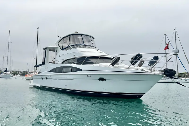 Slide: The Image of 2003 Carver 444 Cockpit Motor Yacht on calm water, surrounded by sailboats. - 6