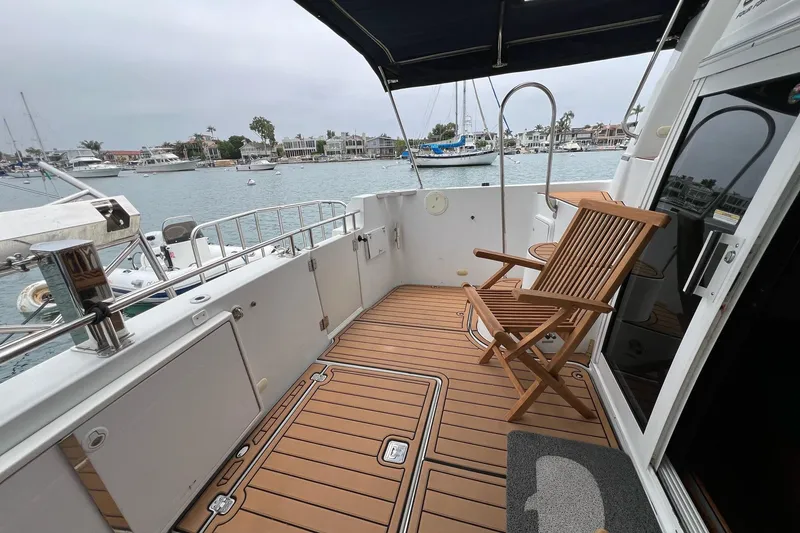 Slide: The Image of 2003 Carver 444 Cockpit Motor Yacht with wooden deck and chair, docked in marina. - 63