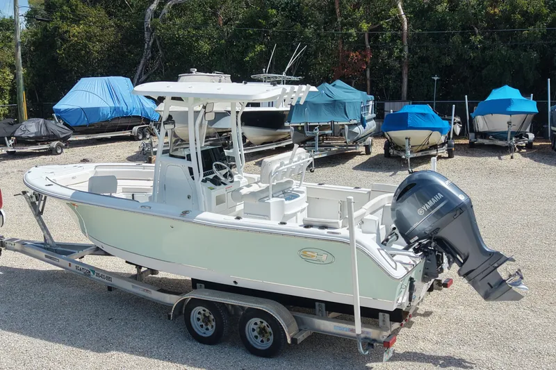 Slide: The Image of 2020 Sea Hunt Ultra 225 boat on trailer, parked in a boatyard with covered boats. - 10