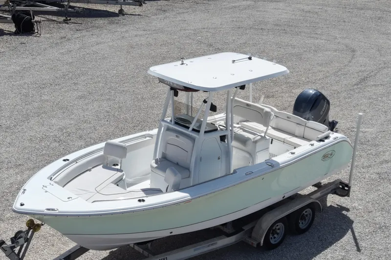 Slide: The Image of 2020 Sea Hunt Ultra 225 boat on trailer, white exterior, parked on gravel. - 11
