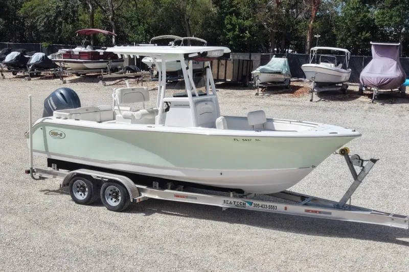 Slide: The Image of 2020 Sea Hunt Ultra 225 boat on trailer in a gravel lot with other boats. - 2