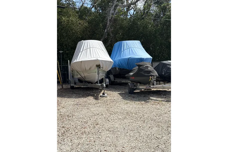 Slide: The Image of Covered 2020 Sea Hunt Ultra 225 boats and jet ski on trailers in storage area. - 21