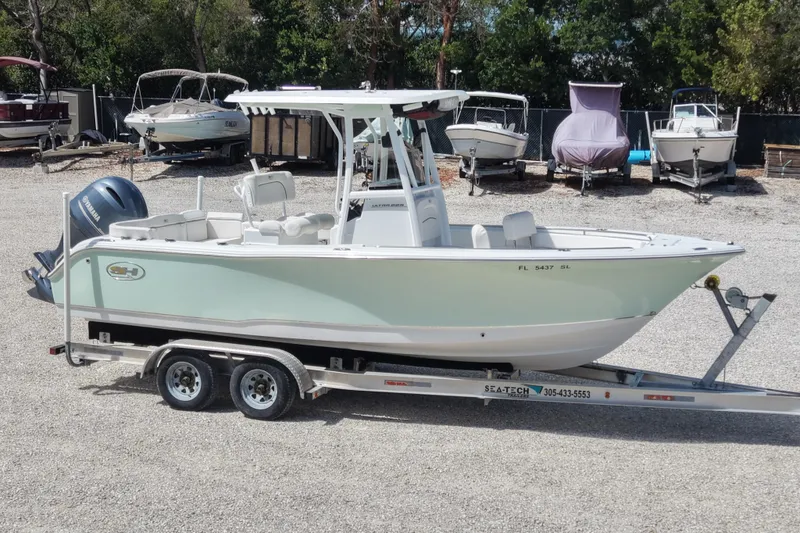 Slide: The Image of 2020 Sea Hunt Ultra 225 boat on trailer, parked in a gravel lot with other boats. - 8