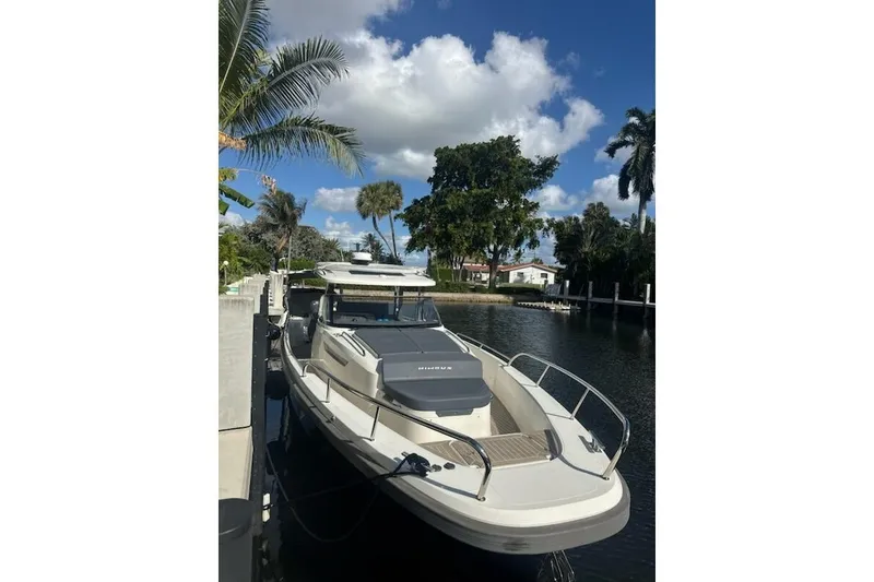 Slide: The Image of 2021 Nimbus T11 boat docked by a canal, surrounded by palm trees and clear skies. - 2