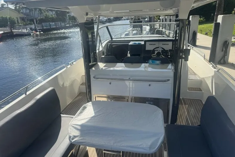 Slide: The Image of 2021 Nimbus T11 boat interior with seating and table on a sunny day. - 5