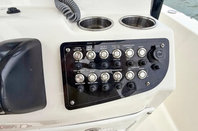 Slide: The Image of Control panel of 2020 NauticStar 251 Hybrid boat with various switches and cup holders. - 14