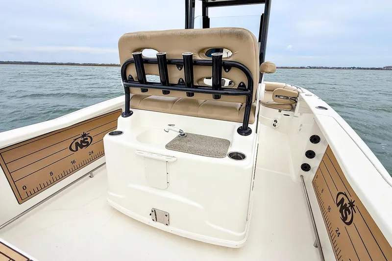 Slide: The Image of 2020 NauticStar 251 Hybrid boat interior with rod holders and seating on the water. - 18