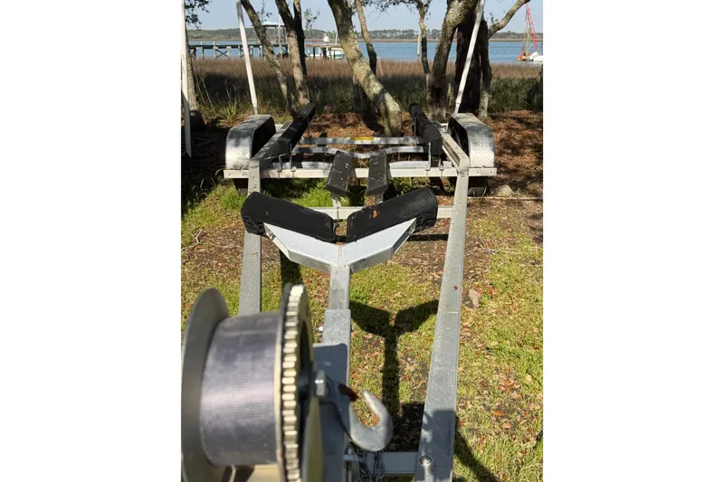 Slide: The Image of Boat trailer for 2020 NauticStar 251 Hybrid, parked near waterfront with trees. - 26