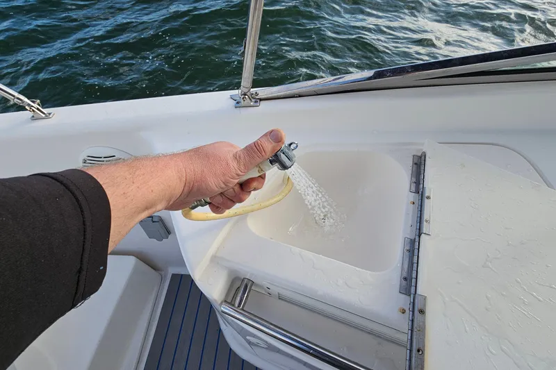 Slide: The Image of Hand using hose on Chaparral 285 SSi boat, 2002 model, near water. - 18