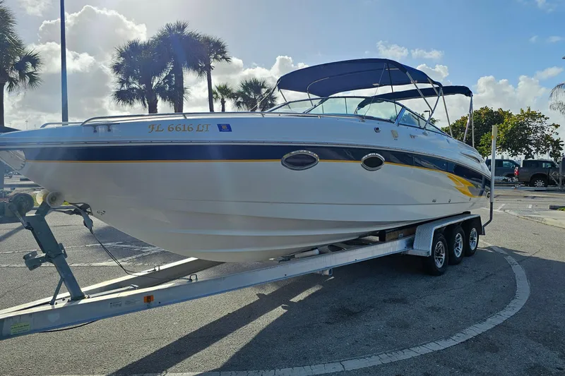 Slide: The Image of 2002 Chaparral 285 SSi boat on trailer, parked under sunny skies with palm trees. - 5