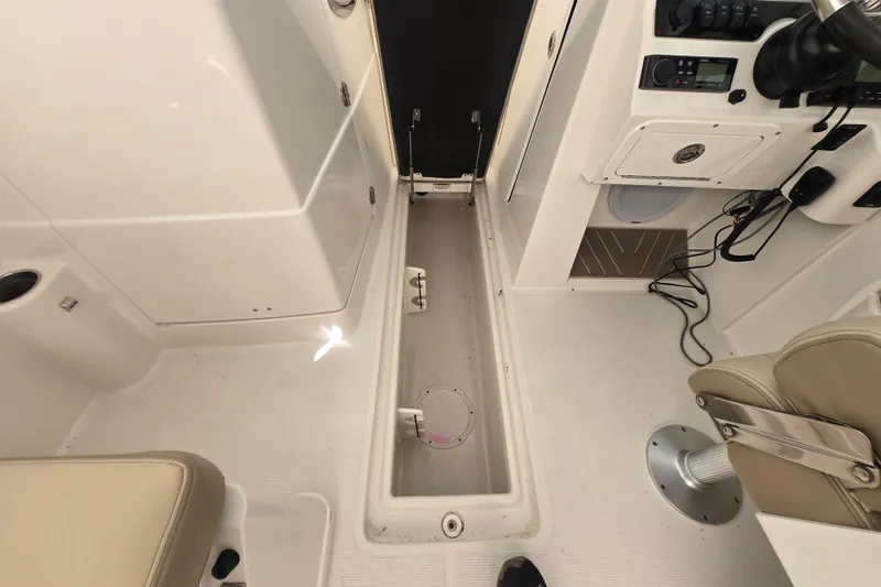 Slide: The Image of 2020 Sailfish 245 DC boat interior with storage compartment and helm controls. - 23