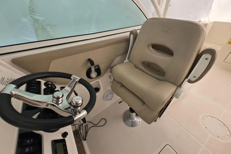 Slide: The Image of 2020 Sailfish 245 DC boat interior with steering wheel and beige captain's chair. - 26