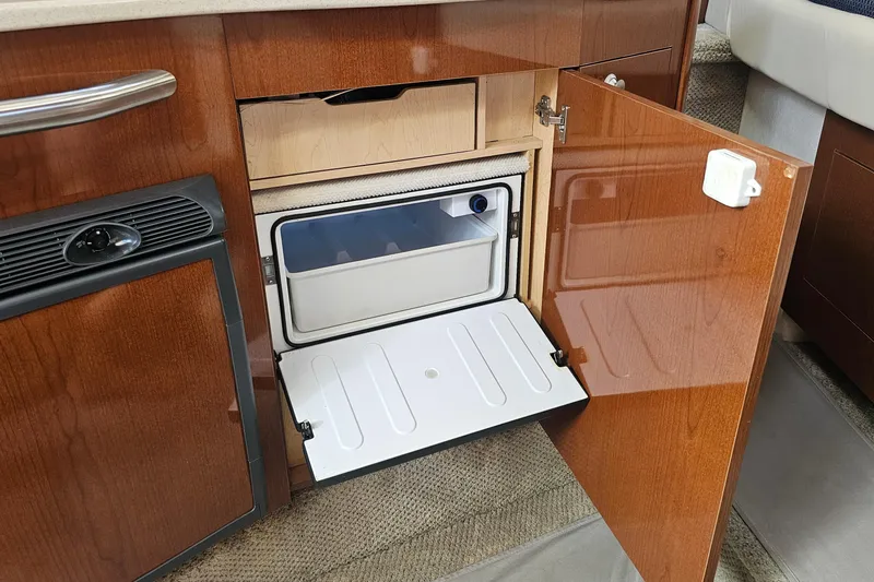 Slide: The Image of 2008 Sea Ray Sundancer 310 interior with open wooden cabinet and mini fridge. - 18