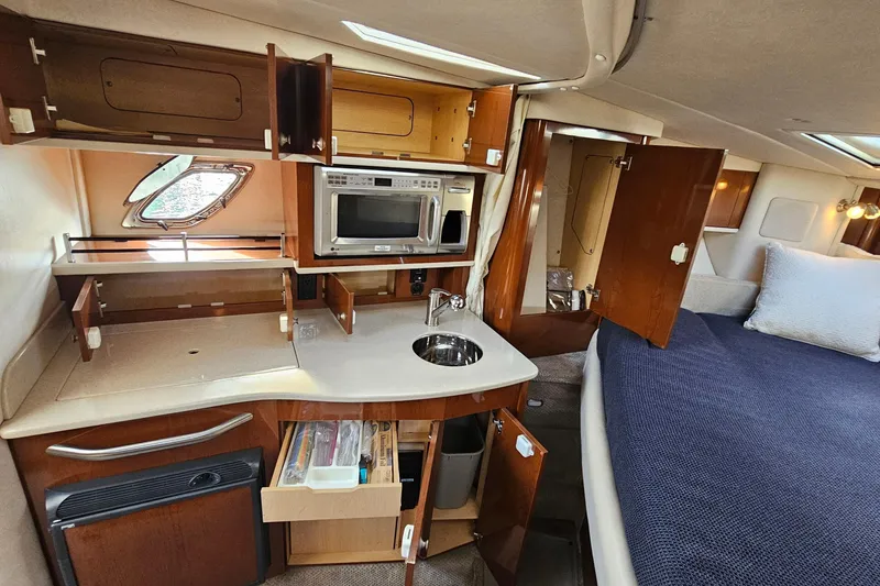 Slide: The Image of 2008 Sea Ray Sundancer 310 cabin interior with kitchenette and bed, featuring wood cabinetry. - 23