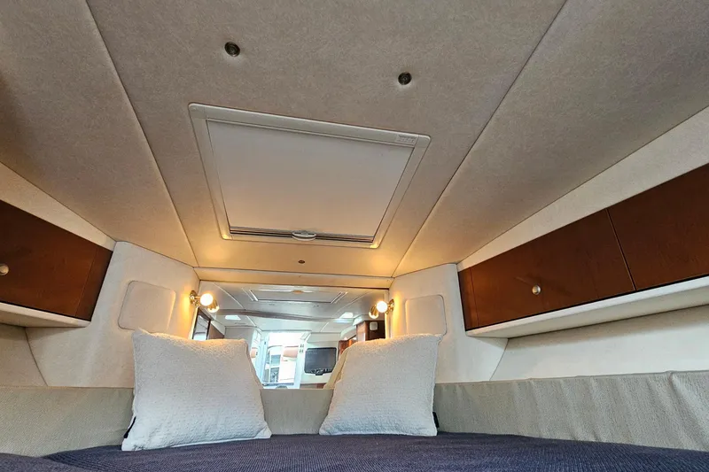 Slide: The Image of 2008 Sea Ray Sundancer 310 cabin interior with cozy bedding and wooden storage cabinets. - 28