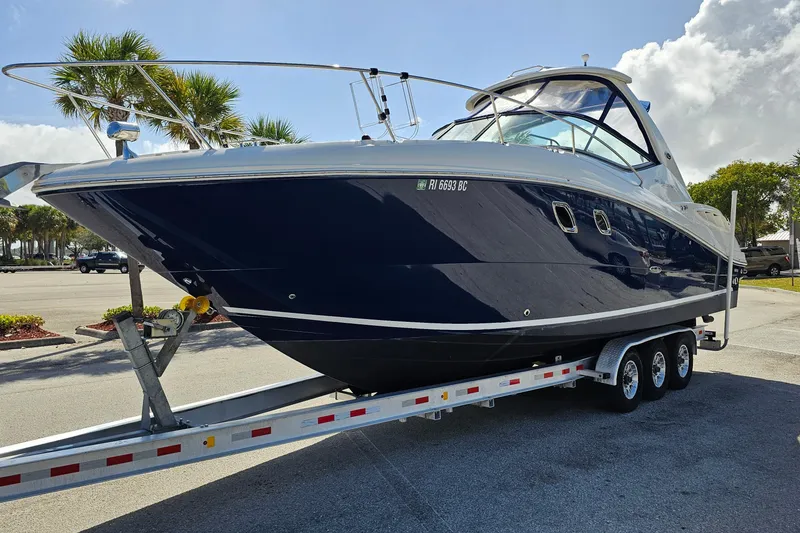 Slide: The Image of 2008 Sea Ray Sundancer 310 boat on trailer, parked in sunny lot with palm trees. - 4