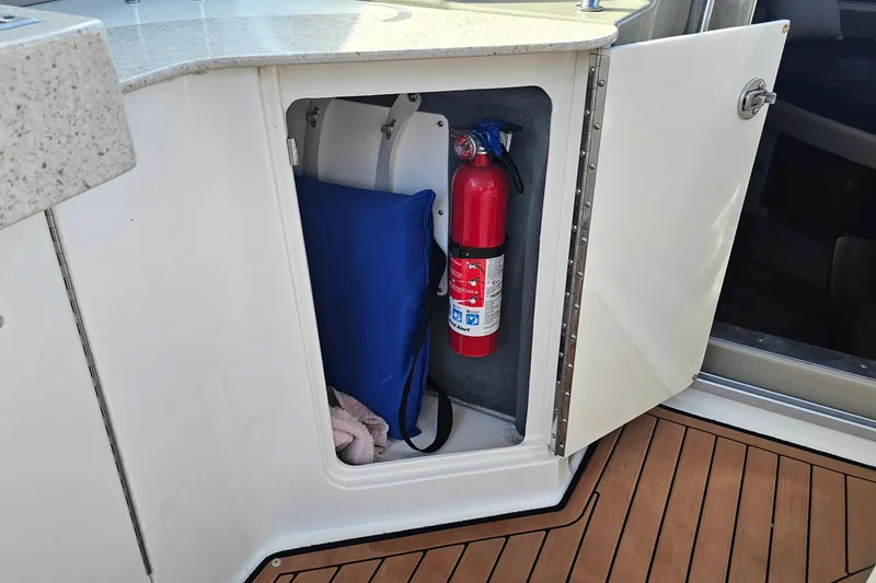 Slide: The Image of Open storage compartment on 2008 Sea Ray Sundancer 310 with fire extinguisher and blue bag. - 55