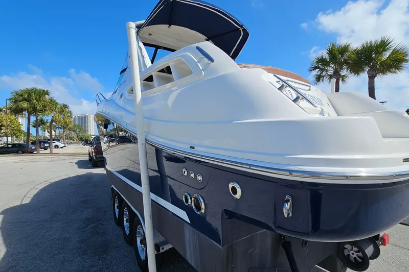 Slide: The Image of 2008 Sea Ray Sundancer 310 yacht on trailer, parked under clear blue sky with palm trees. - 6