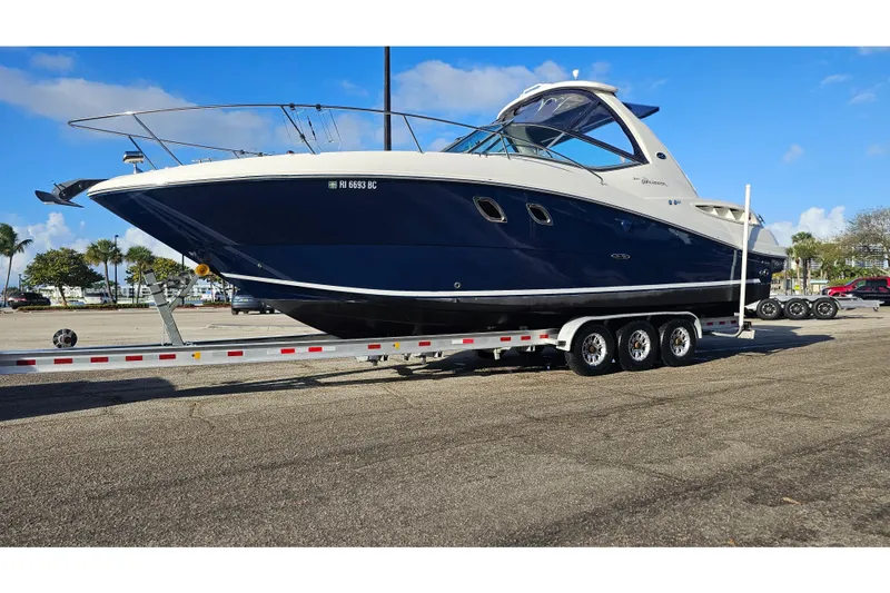 Slide: The Image of 2008 Sea Ray Sundancer 310 boat on trailer, parked outdoors under clear blue sky. - 60