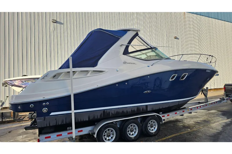Slide: The Image of 2008 Sea Ray Sundancer 310 boat on trailer, blue and white exterior, docked outdoors. - 67