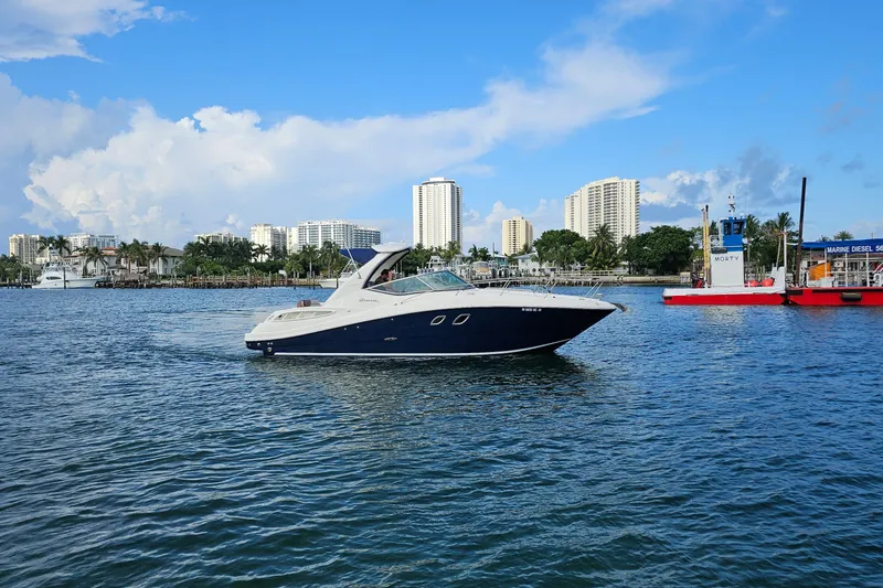Slide: The Image of 2008 Sea Ray Sundancer 310 yacht cruising near a city skyline on a sunny day. - 80