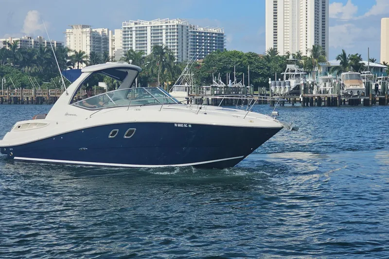 Slide: The Image of 2008 Sea Ray Sundancer 310 cruising in a marina with cityscape background. - 83