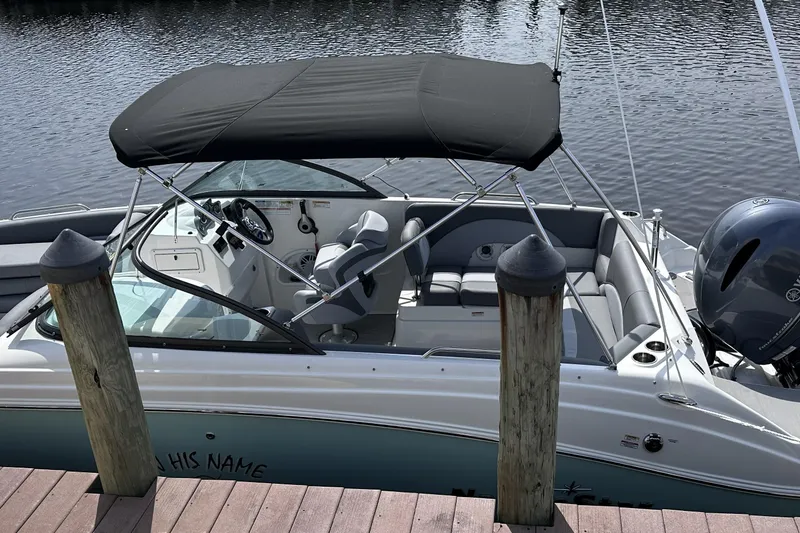 Slide: The Image of 2023 NauticStar 223 DC boat docked, featuring a black canopy and sleek interior design. - 12