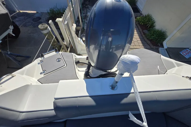 Slide: The Image of 2023 NauticStar 223 DC boat with outboard motor, docked near a garden. - 17