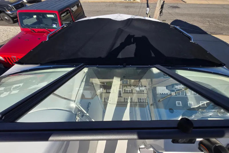 Slide: The Image of 2023 NauticStar 223 DC boat with black cover, parked near red vehicle. - 18