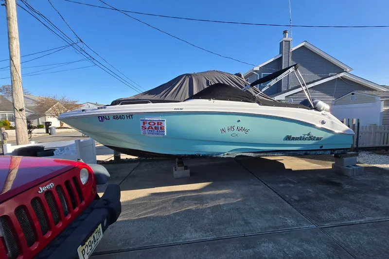 Slide: The Image of 2023 NauticStar 223 DC boat for sale, parked on driveway, covered and elevated. - 20