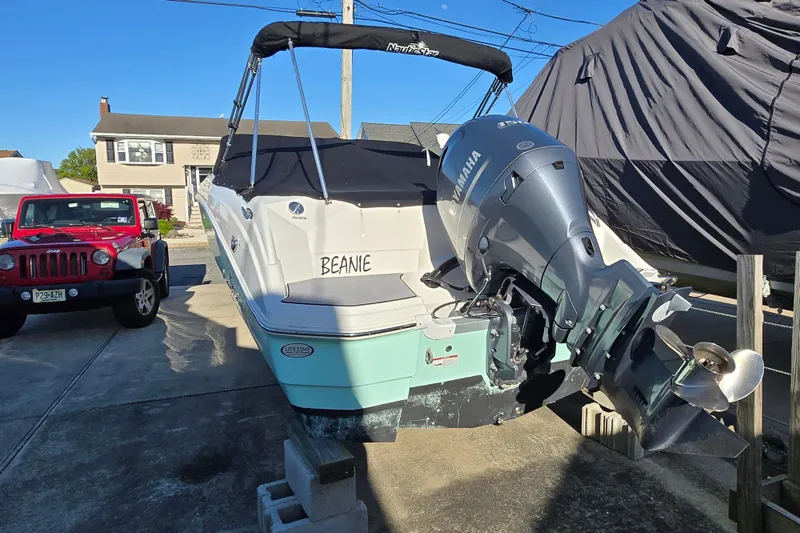 Slide: The Image of 2023 NauticStar 223 DC boat with Yamaha engine, parked beside a red Jeep. - 21
