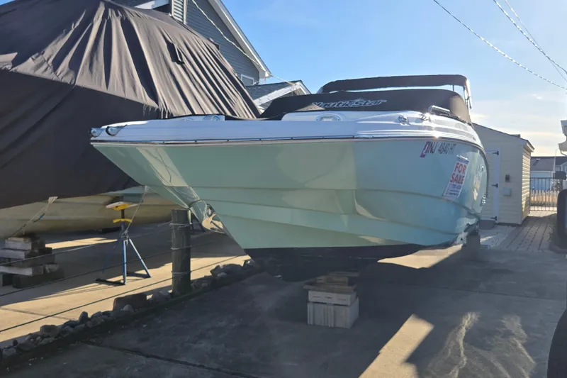 Slide: The Image of 2023 NauticStar 223 DC boat for sale, displayed on blocks in a driveway. - 23
