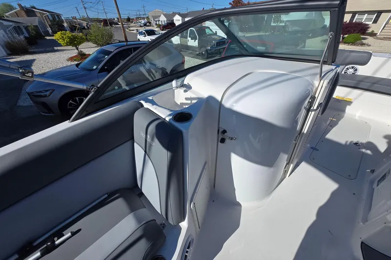 Slide: The Image of 2023 NauticStar 223 DC boat interior with seating and windshield, parked in a residential area. - 8