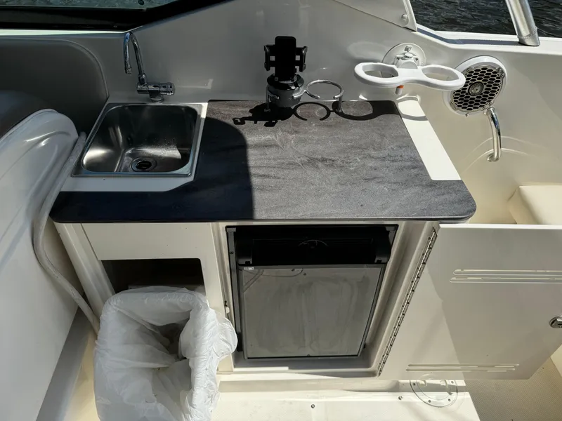 Slide: The Image of 2013 Sea Ray 300 SLX boat kitchenette with sink, mini-fridge, and cup holders. - 11
