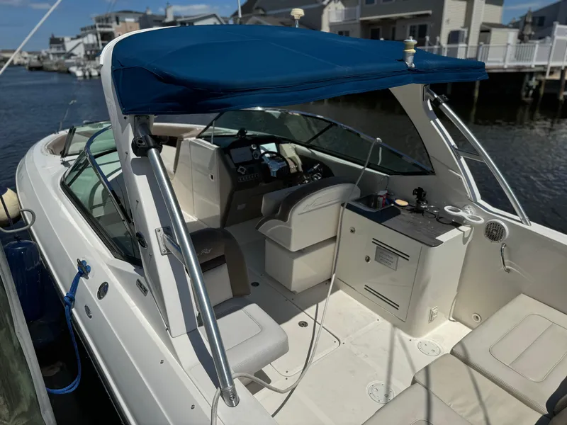 Slide: The Image of 2013 Sea Ray 300 SLX boat docked, featuring a blue canopy and spacious seating area. - 2