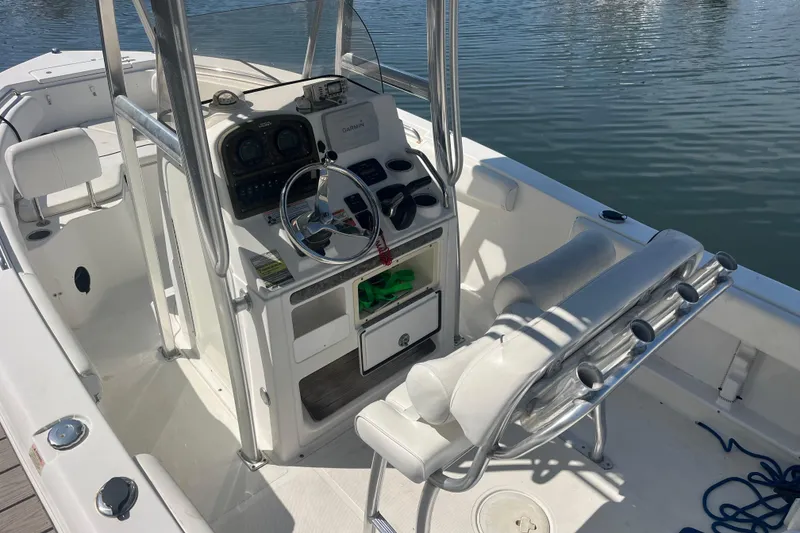 Slide: The Image of 2014 Sea Hunt Ultra 211 boat interior with steering console and seating, docked on calm water. - 10